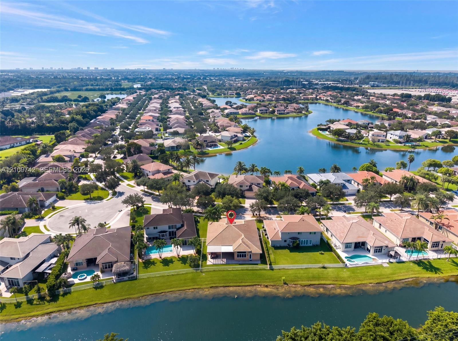 Aerial perspective of a residential property featuring a tiled roof, rear covered patio, and direct waterfront placement on a large lake