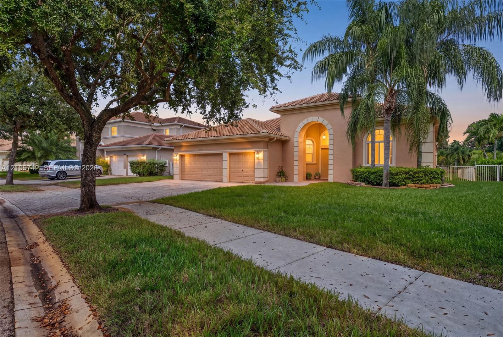 Stucco exterior featuring an arched entryway, tile roof, two-car garage, and paved driveway