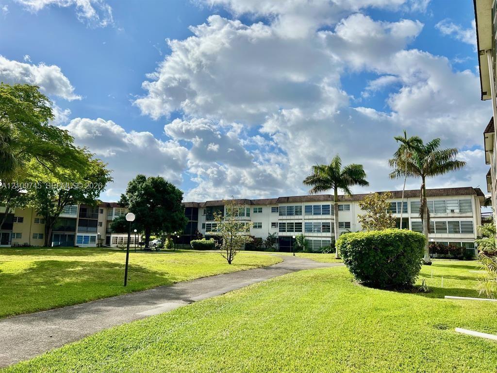 Expansive landscaped grounds featuring mature palm trees, paved walkways, and manicured lawns
