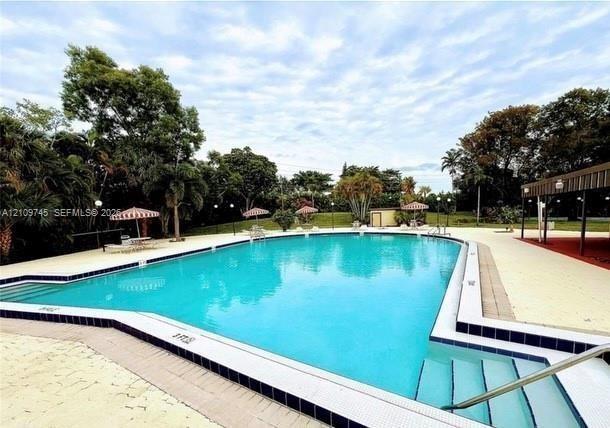 In-ground swimming pool with a tiled perimeter, integrated steps, metal handrails, and a concrete deck surround