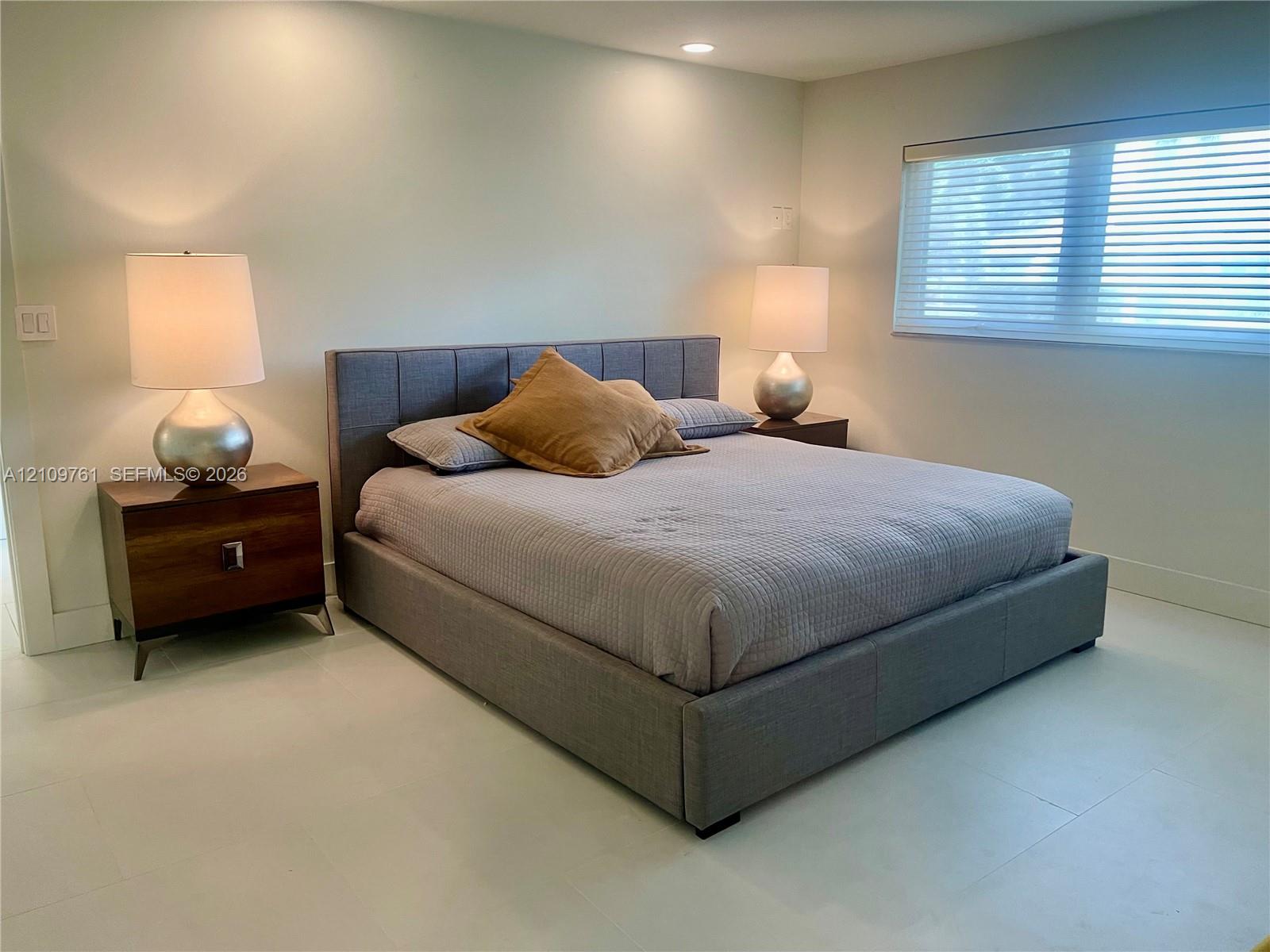 Neutral-toned interior space featuring light-colored flooring, recessed lighting, and a window with horizontal blinds