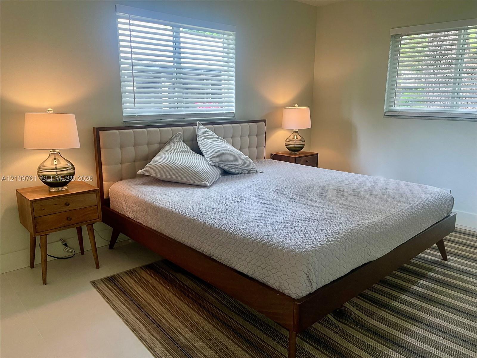 Neutral-toned interior space featuring light-colored flooring and dual windows equipped with horizontal blinds