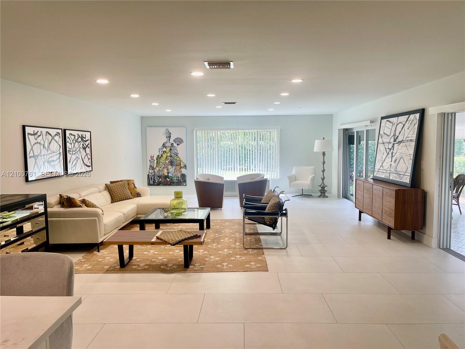 Spacious living area featuring large-format tile flooring, recessed ceiling lighting, and sliding glass doors Spacious living area featuring large-format tile flooring, recessed ceiling lighting, and sliding glass doors