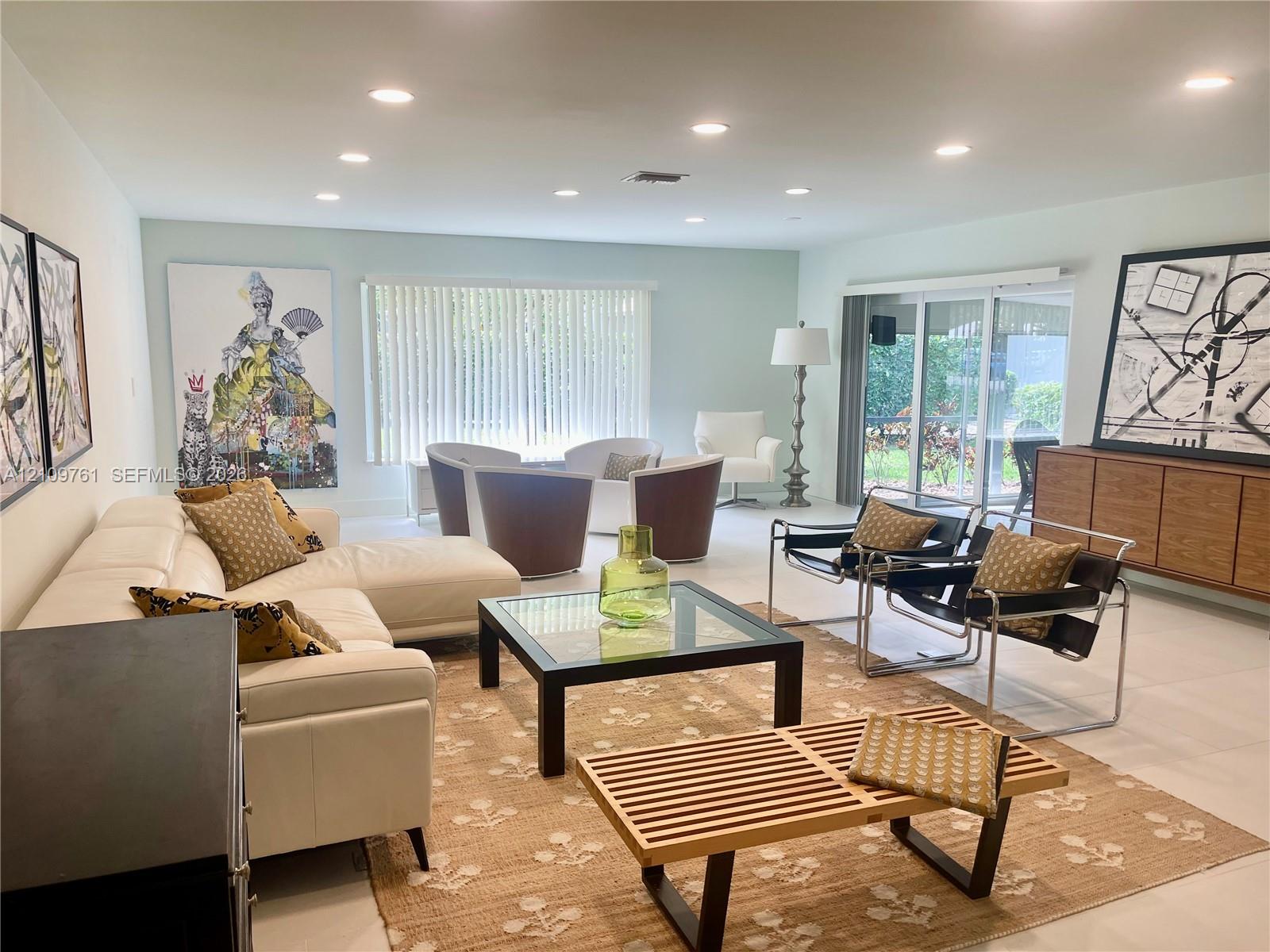 Open-concept living space featuring neutral tile flooring, recessed lighting, and sliding glass doors Open-concept living space featuring neutral tile flooring, recessed lighting, and sliding glass doors