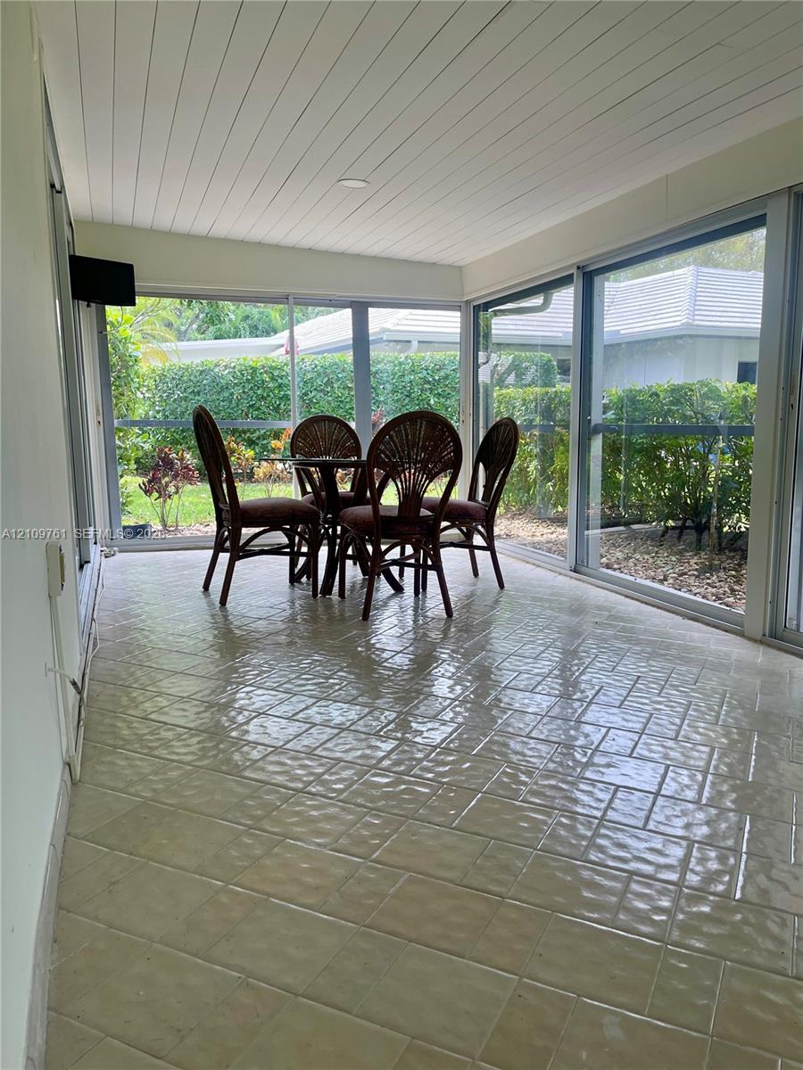 Enclosed patio featuring floor-to-ceiling glass paneling, tile flooring, and a beadboard ceiling