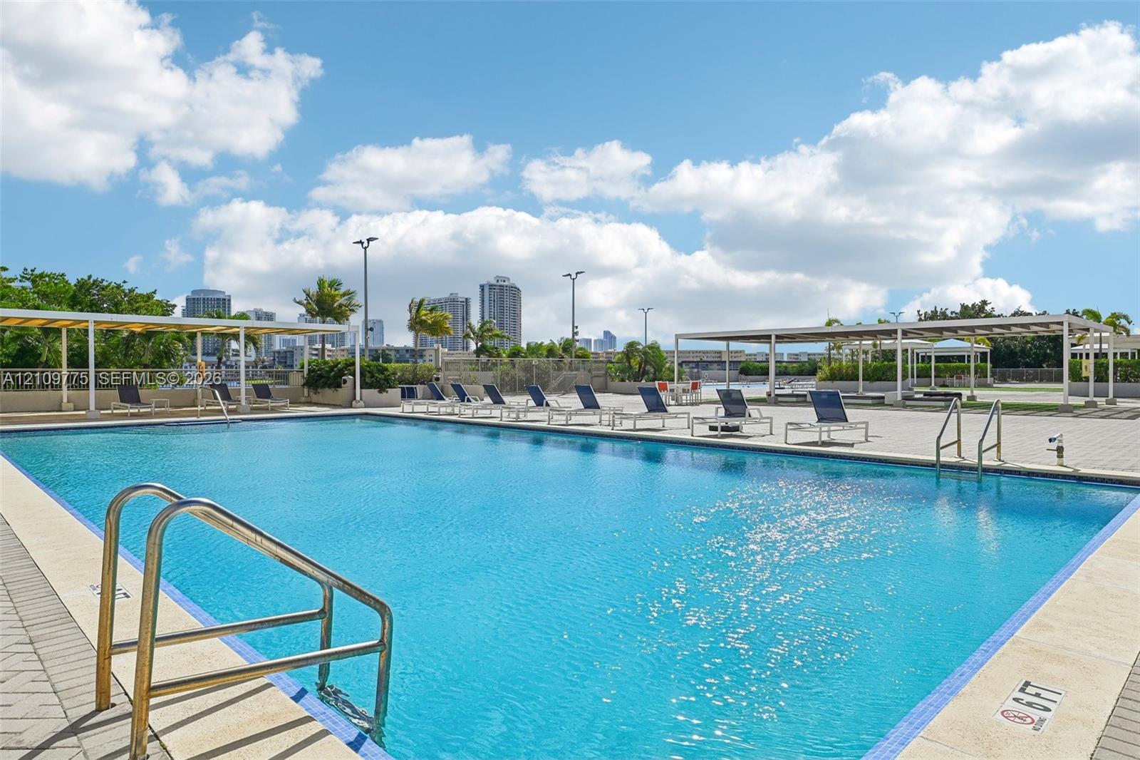 Swimming pool featuring a stone-tile deck, metal entry ladders, and pergola-covered areas