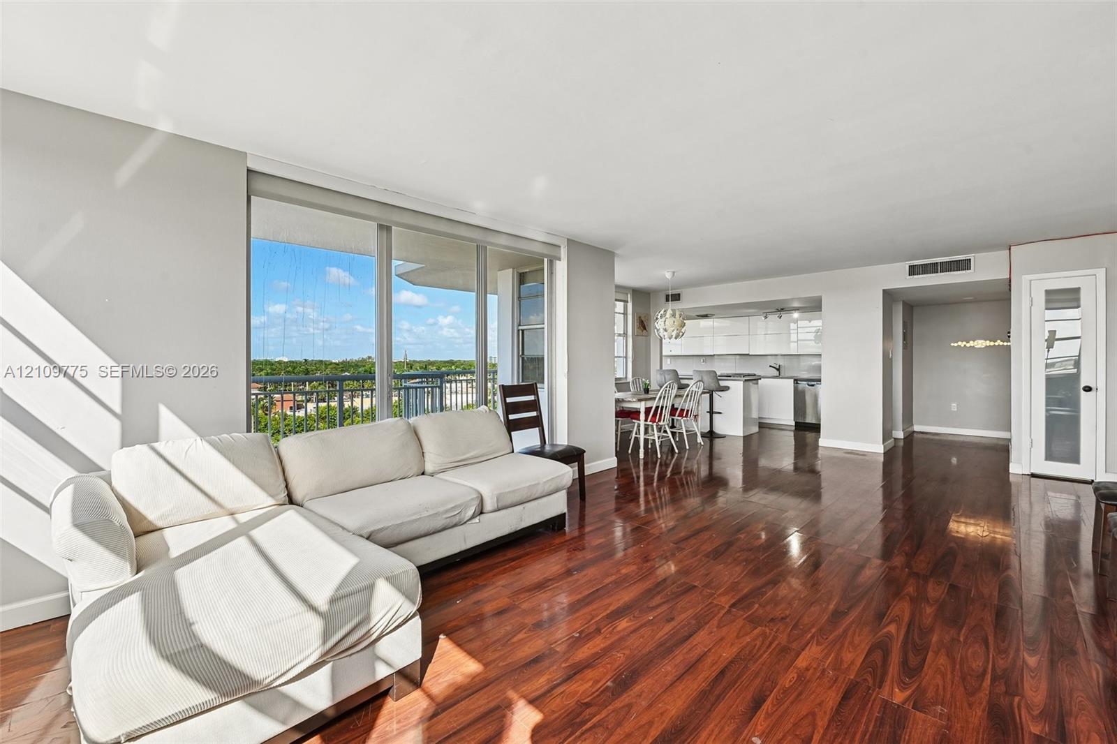 Open-concept floor plan with wood-finish flooring, floor-to-ceiling windows, and access to a private balcony