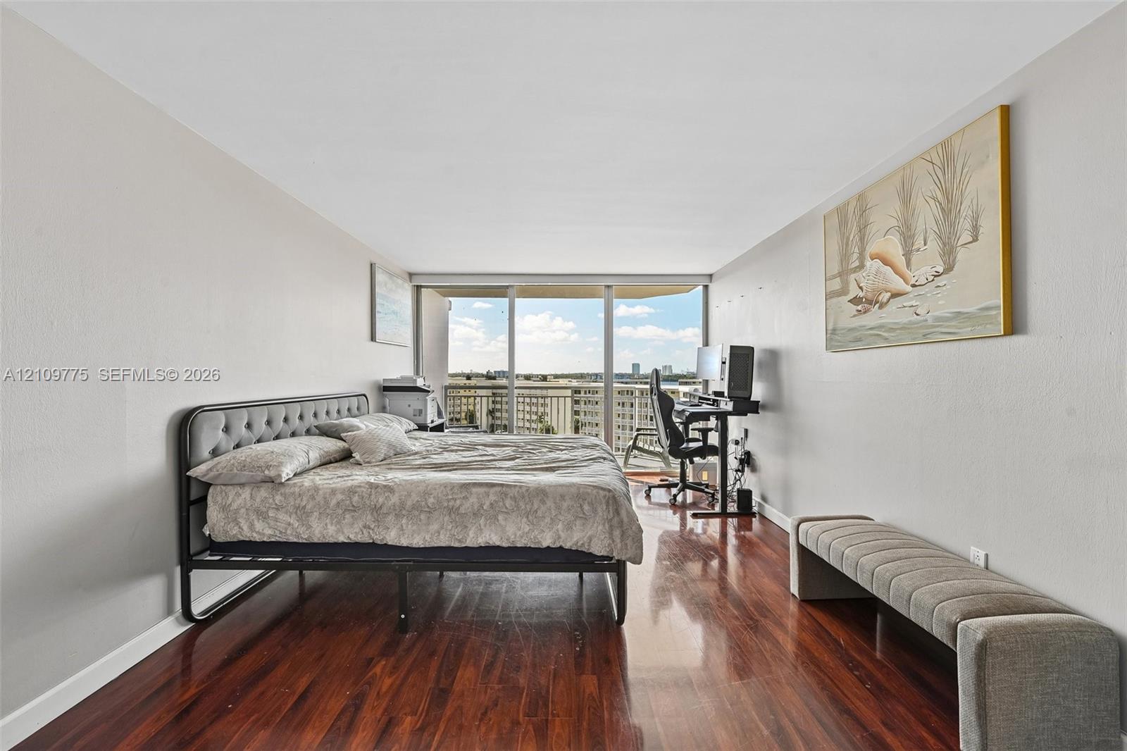 Wood-finish flooring, neutral wall tones, and floor-to-ceiling glass sliding doors opening to an exterior balcony