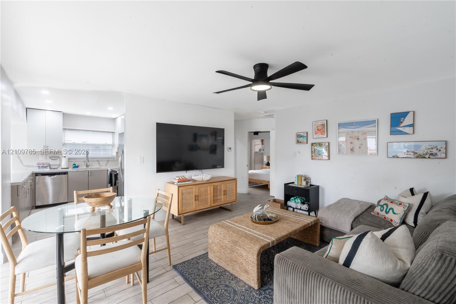 Open-concept living space featuring wood-finish tile flooring, recessed ceiling lighting, a matte black multi-blade ceiling fan, and neutral wall tones
