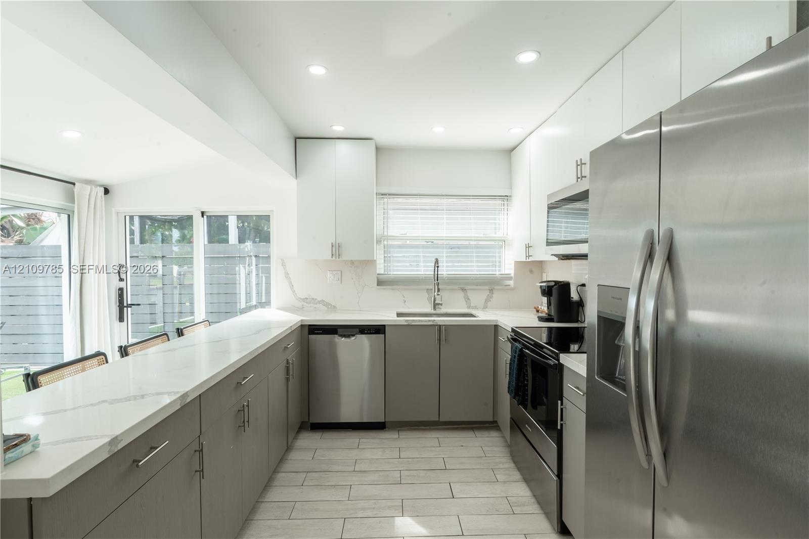 Kitchen featuring stone-finish countertops, stainless steel appliances, flat-panel cabinetry, and tile flooring