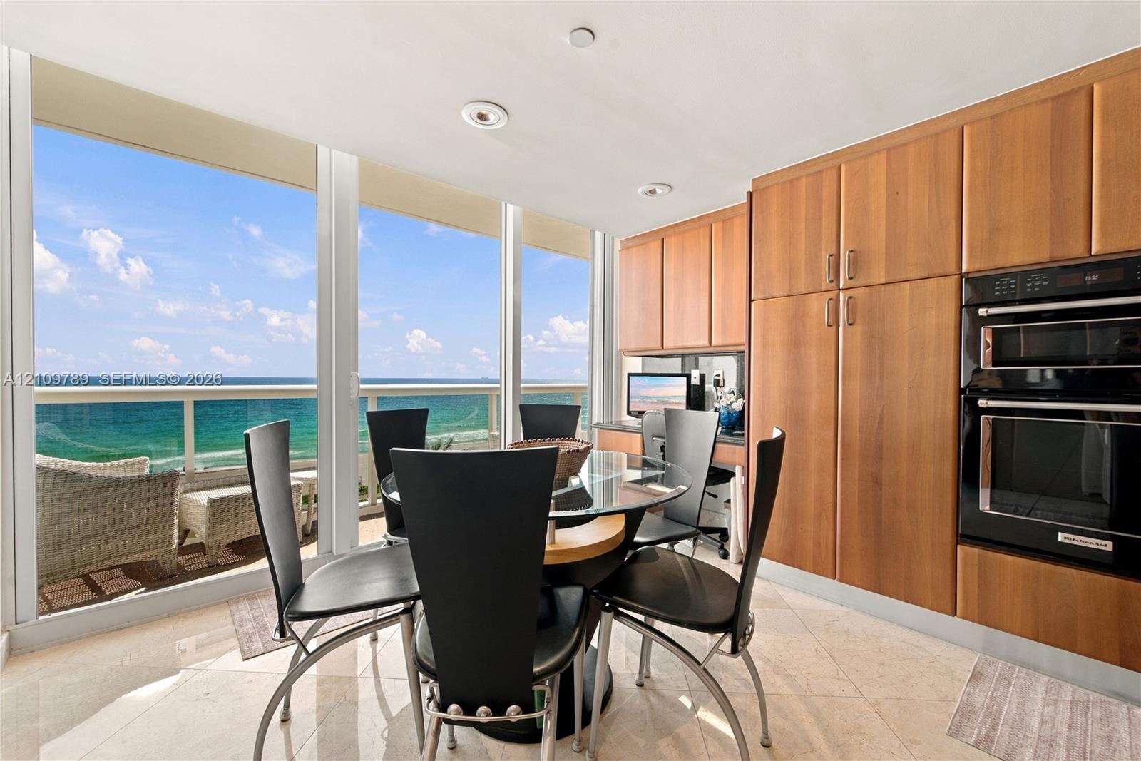 Floor-to-ceiling windows, natural stone flooring, custom wood-finish cabinetry, built-in double wall oven, and balcony access