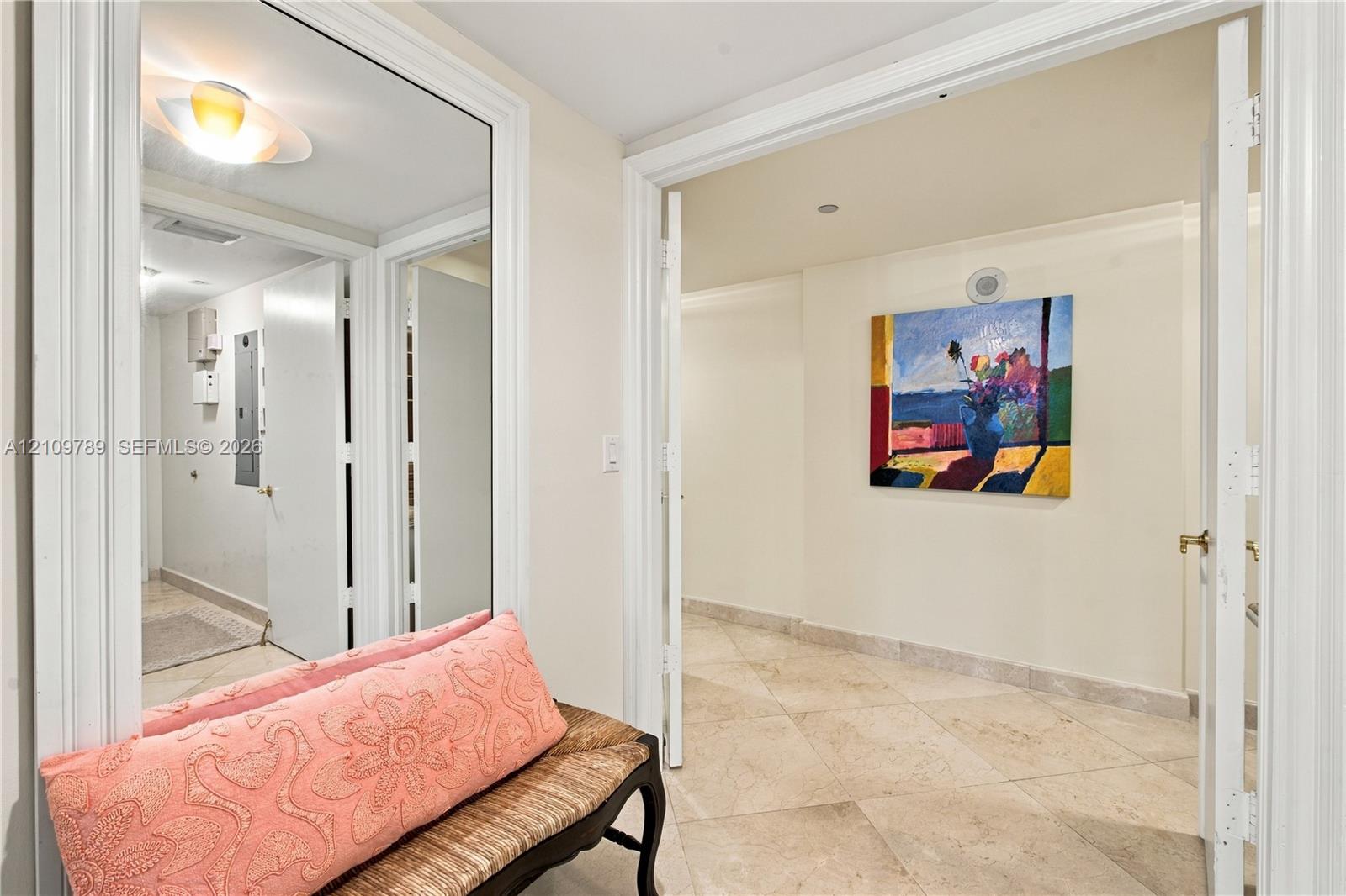 Neutral stone flooring, large wall-mounted mirror, and detailed door casing