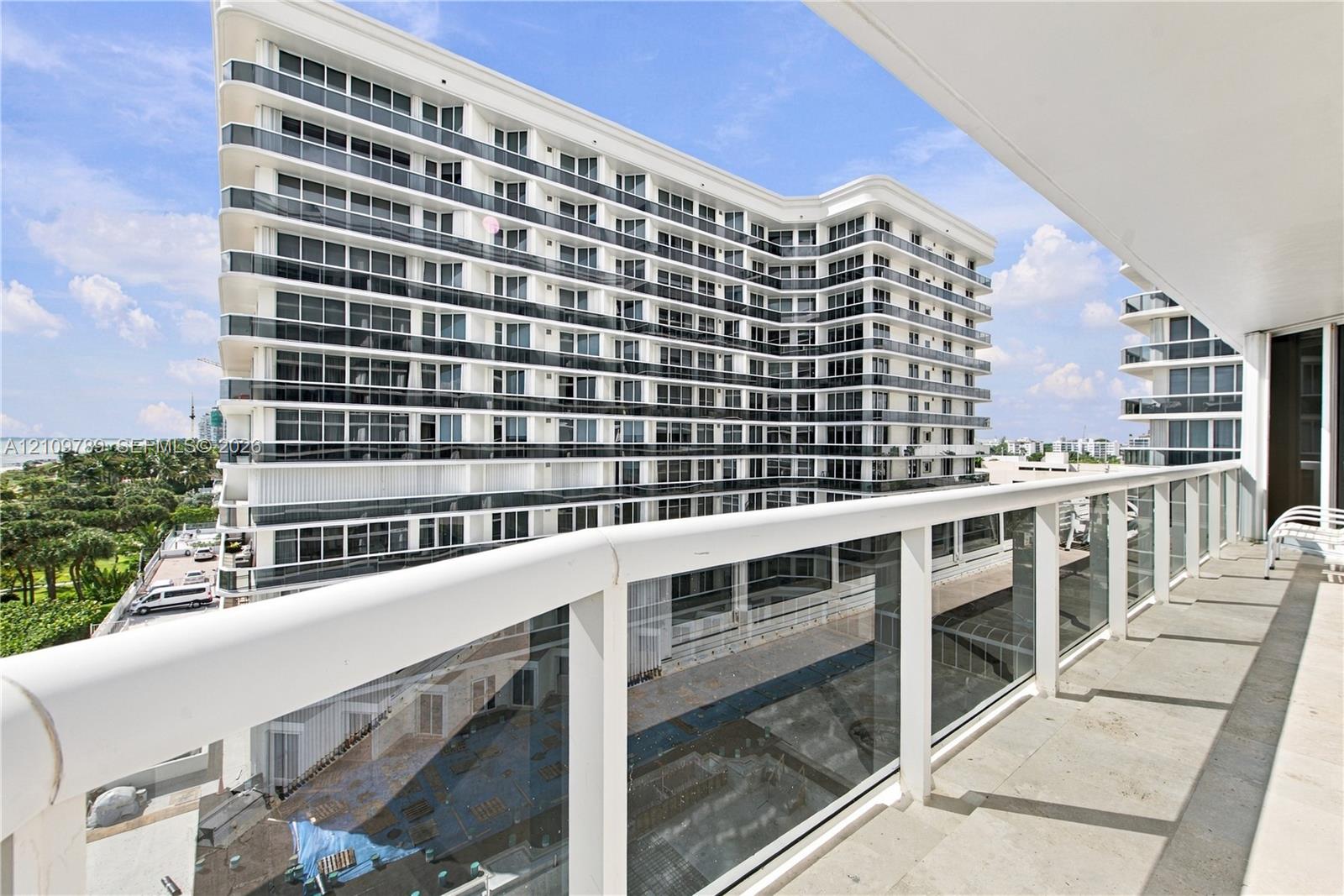 Private balcony featuring a glass panel railing with a top white handrail and large-format stone flooring