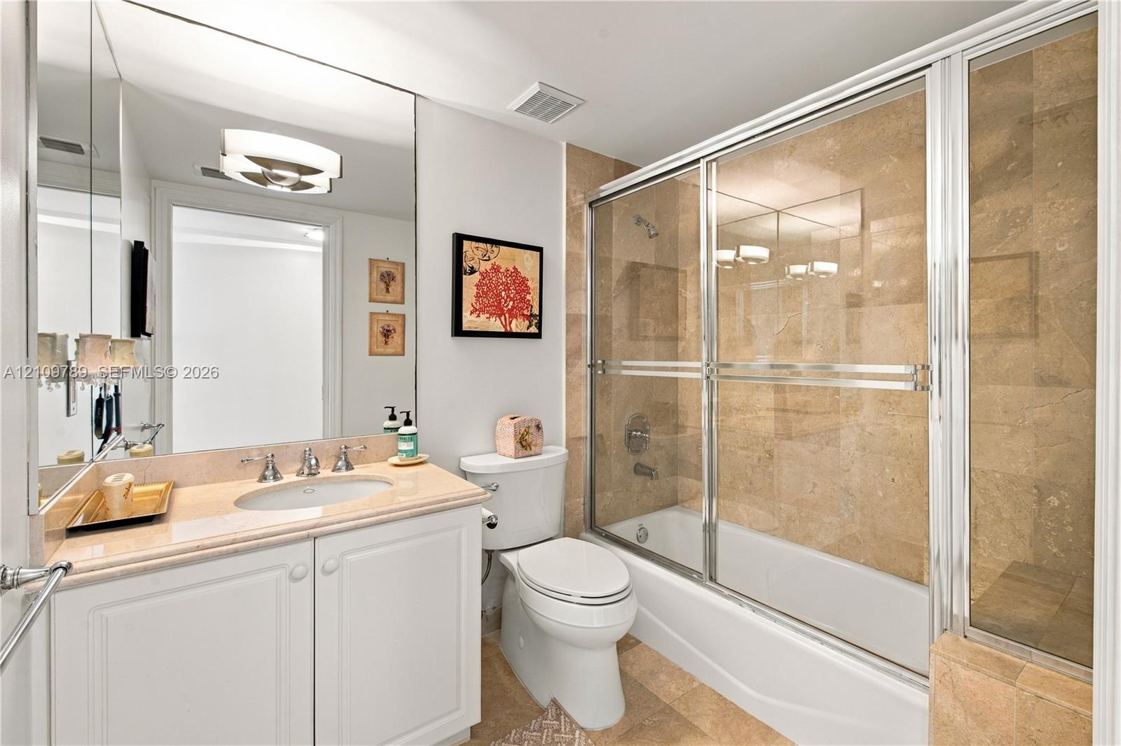 Bathroom featuring a white vanity with a stone countertop, undermount sink, full-width mirror, and a tub-shower combination with floor-to-ceiling tile surround