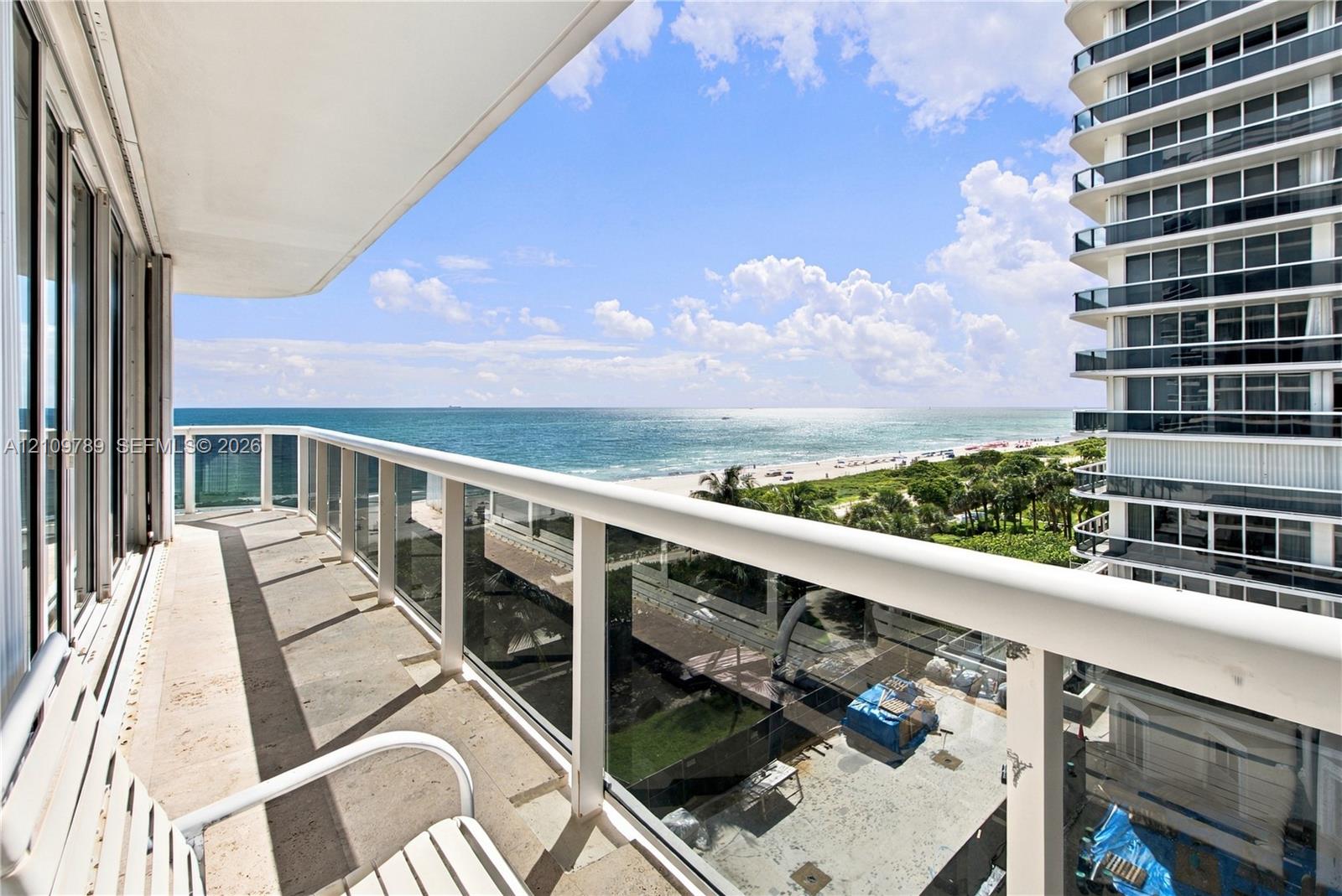 Covered balcony featuring stone flooring and a white railing with glass panels