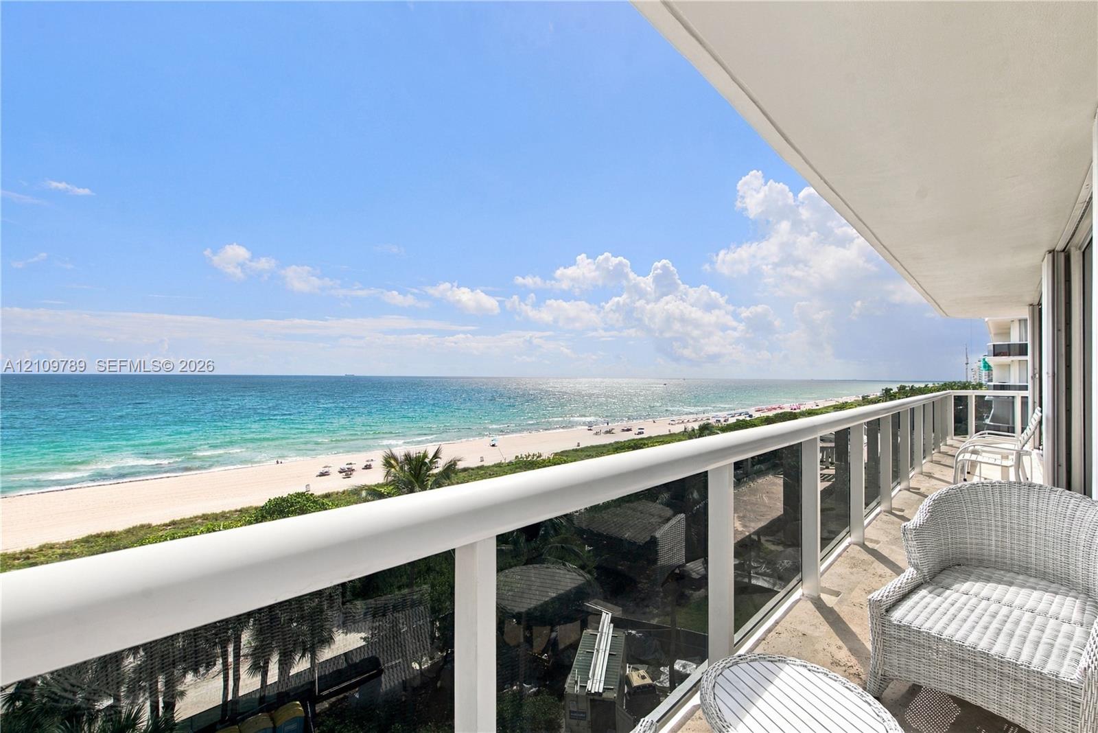 Expansive balcony featuring a glass and white-railing enclosure, stone flooring, and unobstructed oceanfront scenery