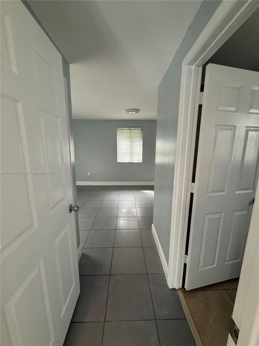 Six-panel interior doors, neutral-toned wall paint, and large-format ceramic tile flooring