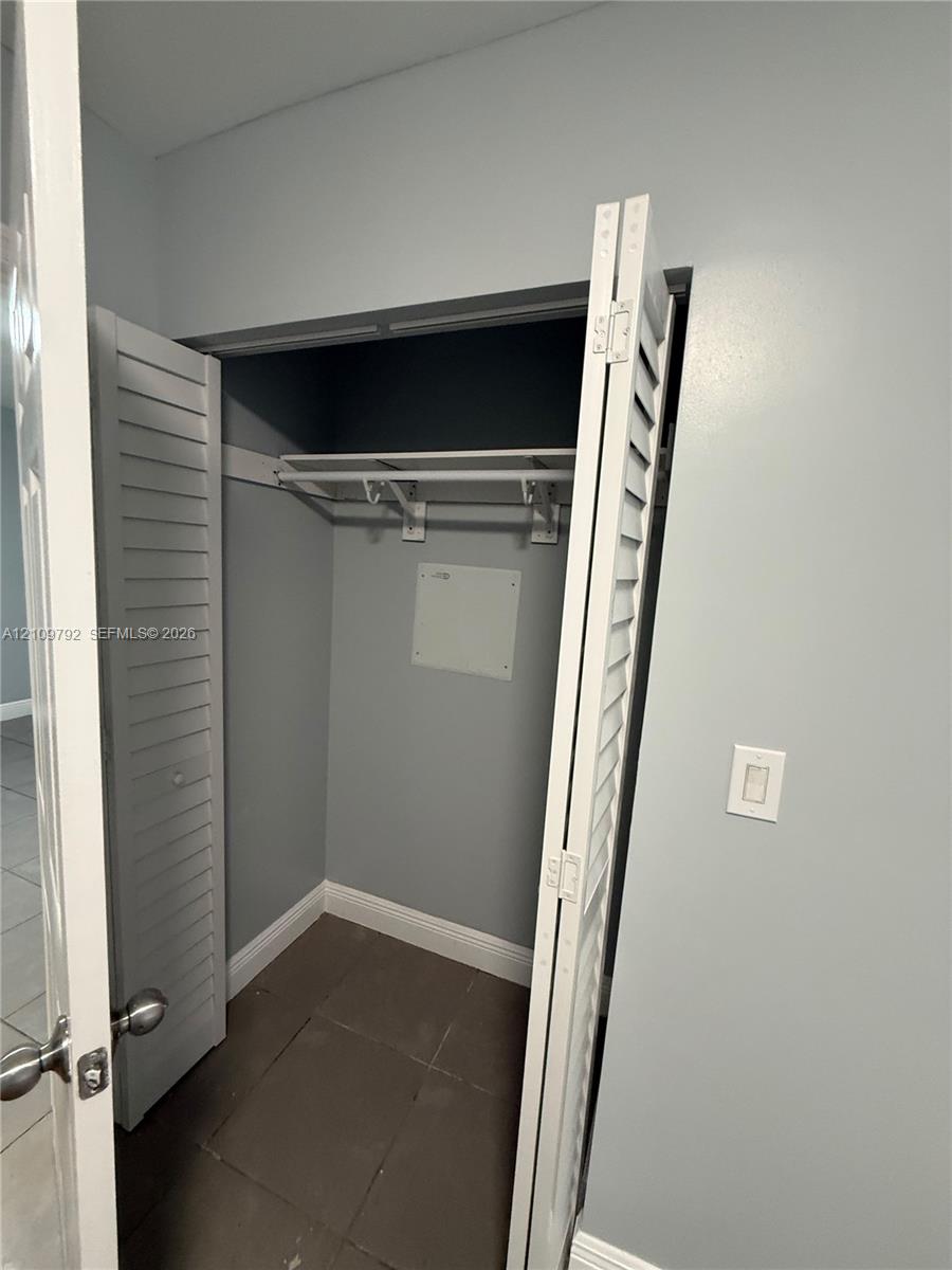 Closet featuring white louvered bifold doors, an integrated upper shelf with a hanging rod, and tile flooring