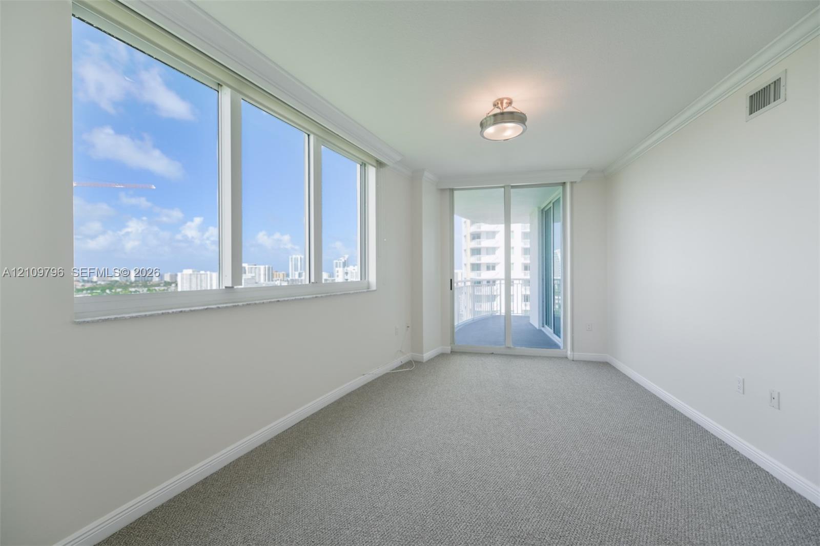 Expansive floor-to-ceiling windows, sliding glass door, neutral carpeting, crown molding, and semi-flush mount ceiling fixture