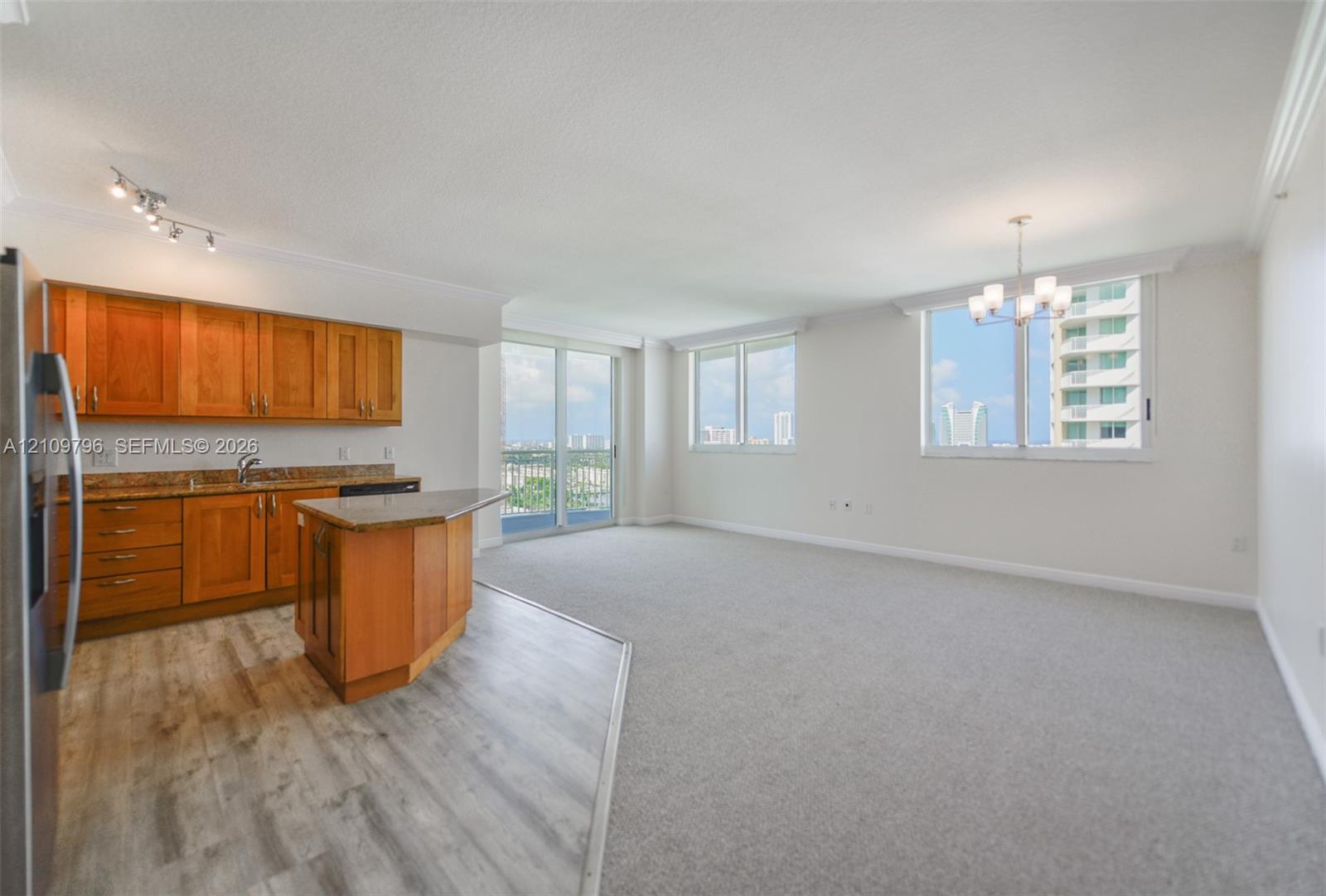 Kitchen featuring wood cabinetry, stone countertops, and an integrated breakfast bar, complemented by neutral carpeting and multi-pane windows