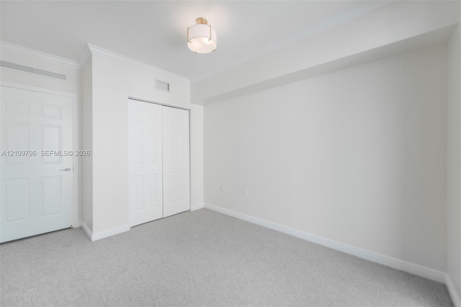 Neutral-toned wall-to-wall carpeting, crown molding, multi-panel doors, and a semi-flush mount drum light fixture