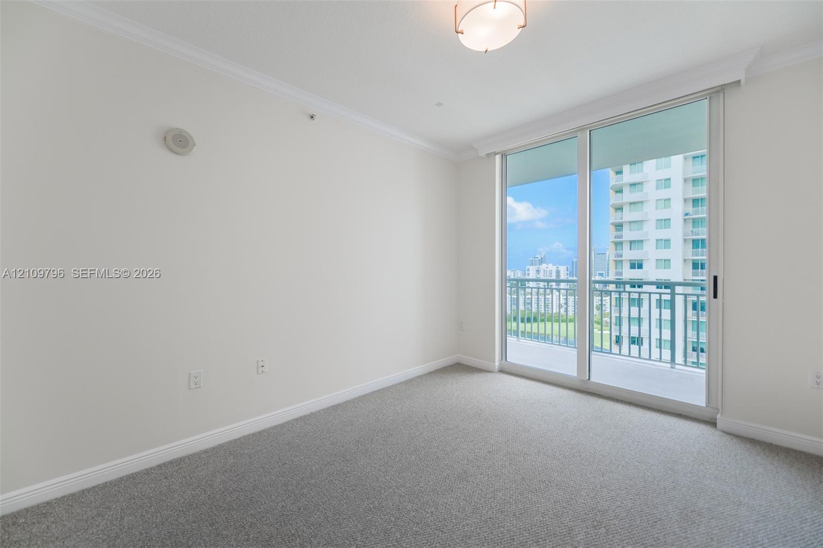 Floor-to-ceiling sliding glass door, private balcony, neutral wall-to-wall carpeting, and crown molding