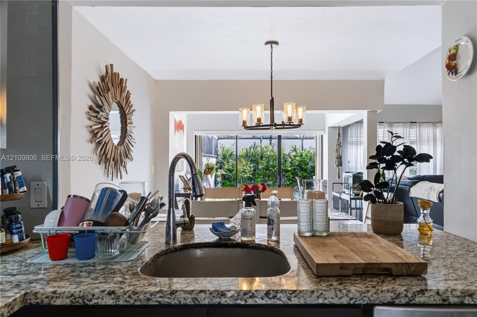 Kitchen featuring stone countertops, an undermount sink with a gooseneck faucet, and a multi-arm pendant light fixture