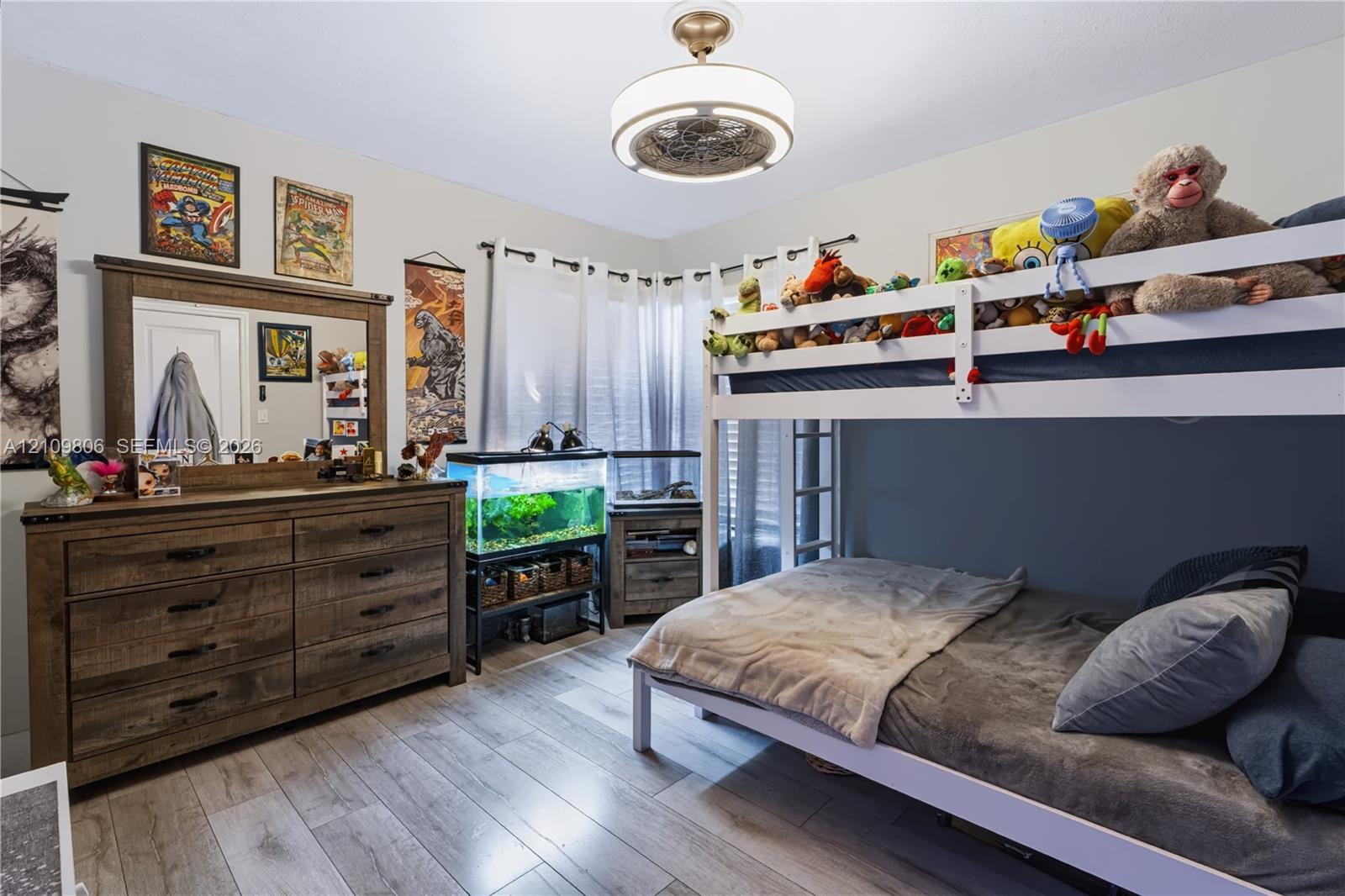 Wood-finish flooring, neutral wall color, and a modern drum-style ceiling light fixture with a decorative central fan