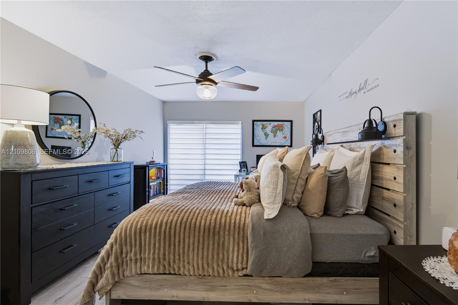 Neutral-toned interior featuring wood-finish flooring, a contemporary ceiling fan with integrated lighting, and sliding glass doors with horizontal blinds