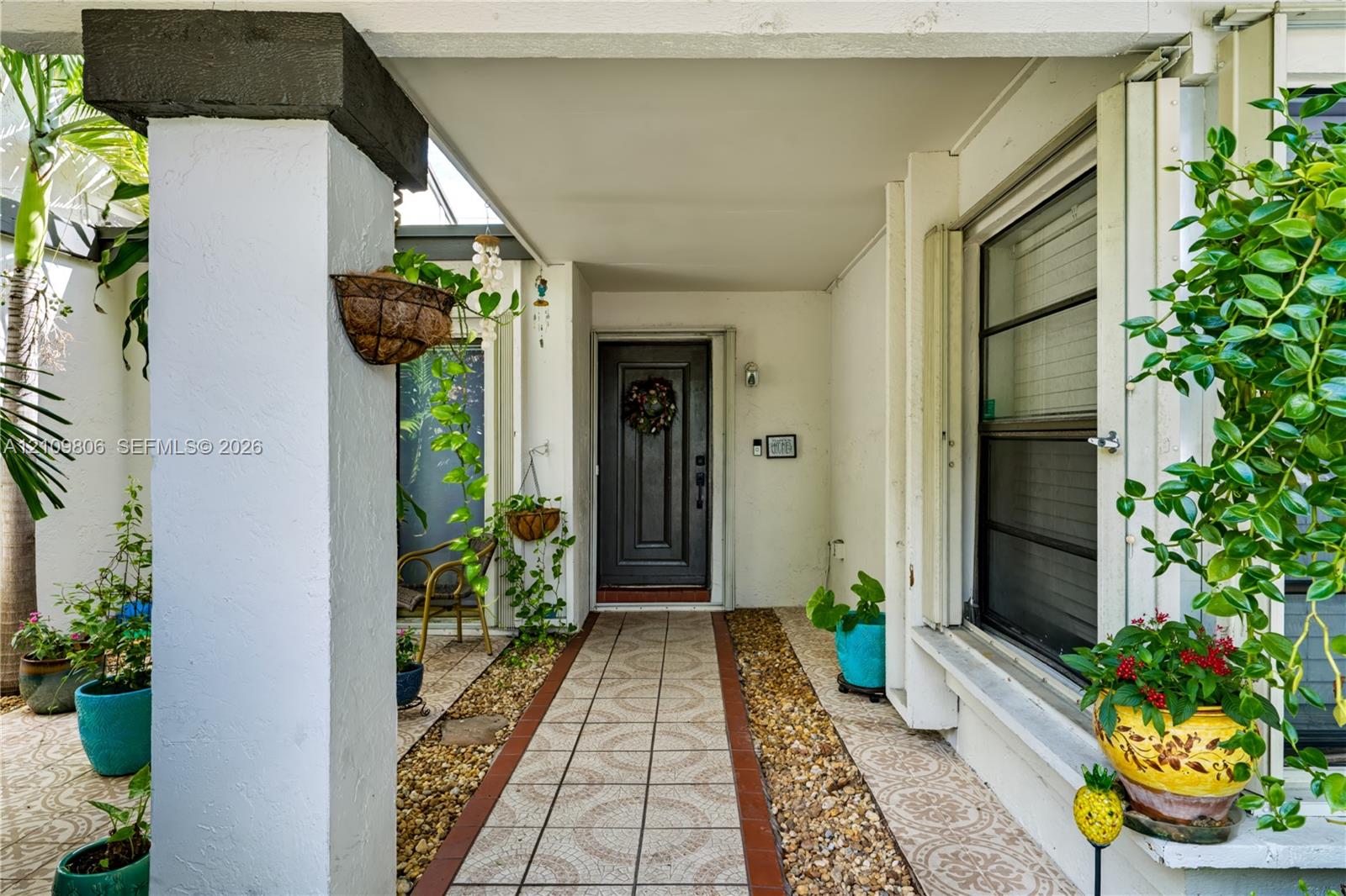 Covered entryway featuring a dark-toned solid core door, decorative ceramic floor tile, and a natural stone border