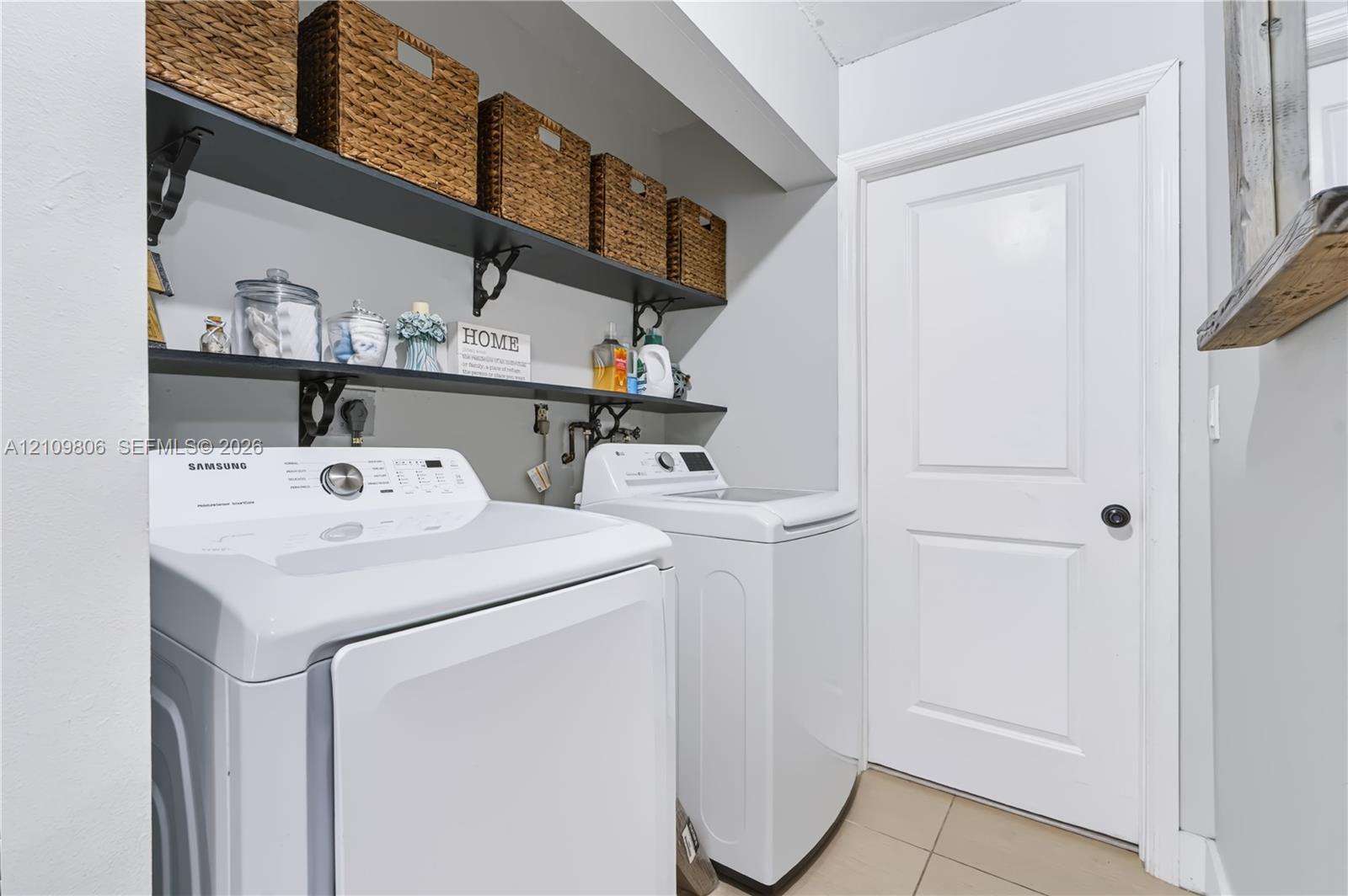 Laundry area featuring dual wall-mounted black shelving units with decorative metal brackets and tile flooring