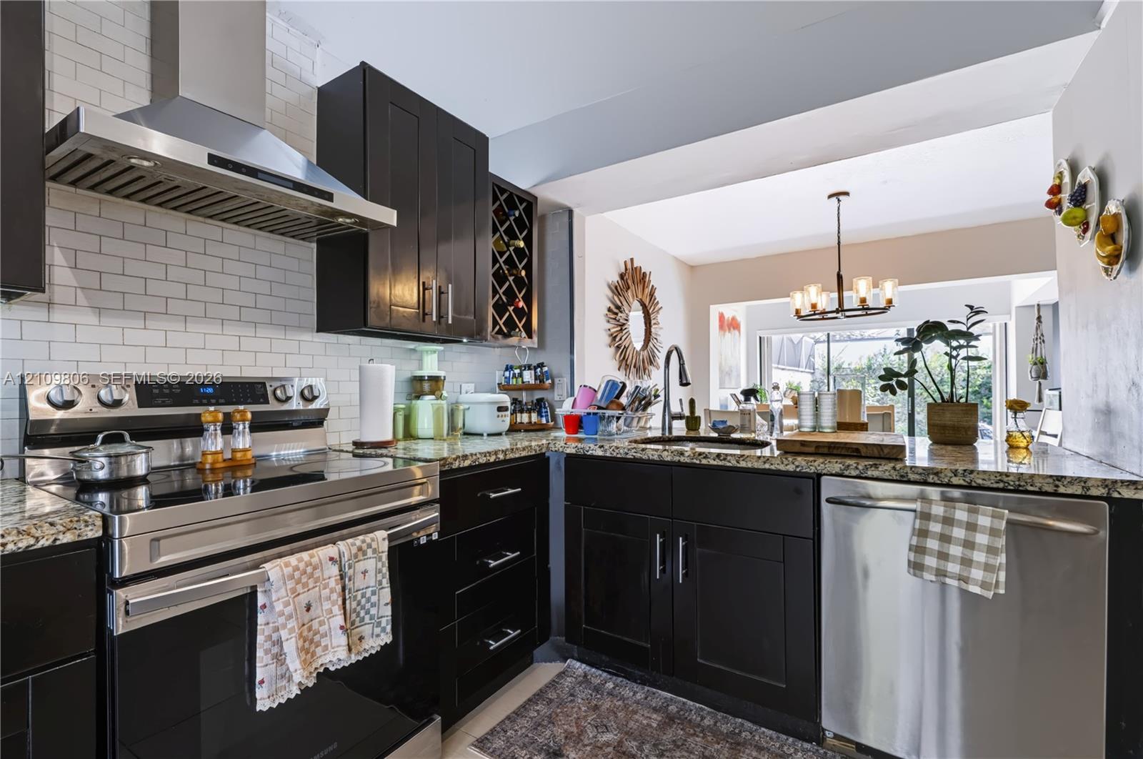 Kitchen featuring dark cabinetry, stone-surface countertops, subway tile backsplash, stainless steel appliances, and a built-in wine rack