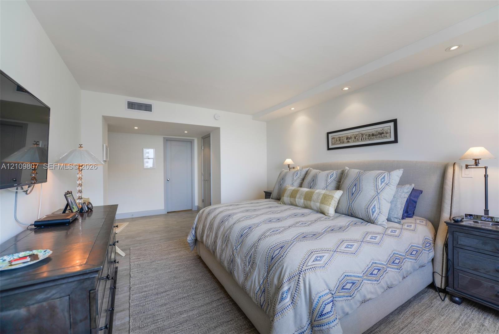 Neutral interior space featuring recessed ceiling lighting and wood-finish flooring