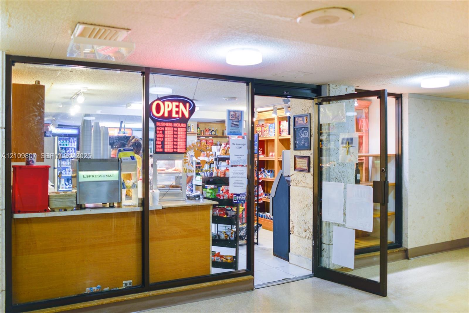 Commercial storefront featuring an aluminum-framed glass entrance, wood-finish transaction counter, recessed ceiling lighting, and built-in wood shelving