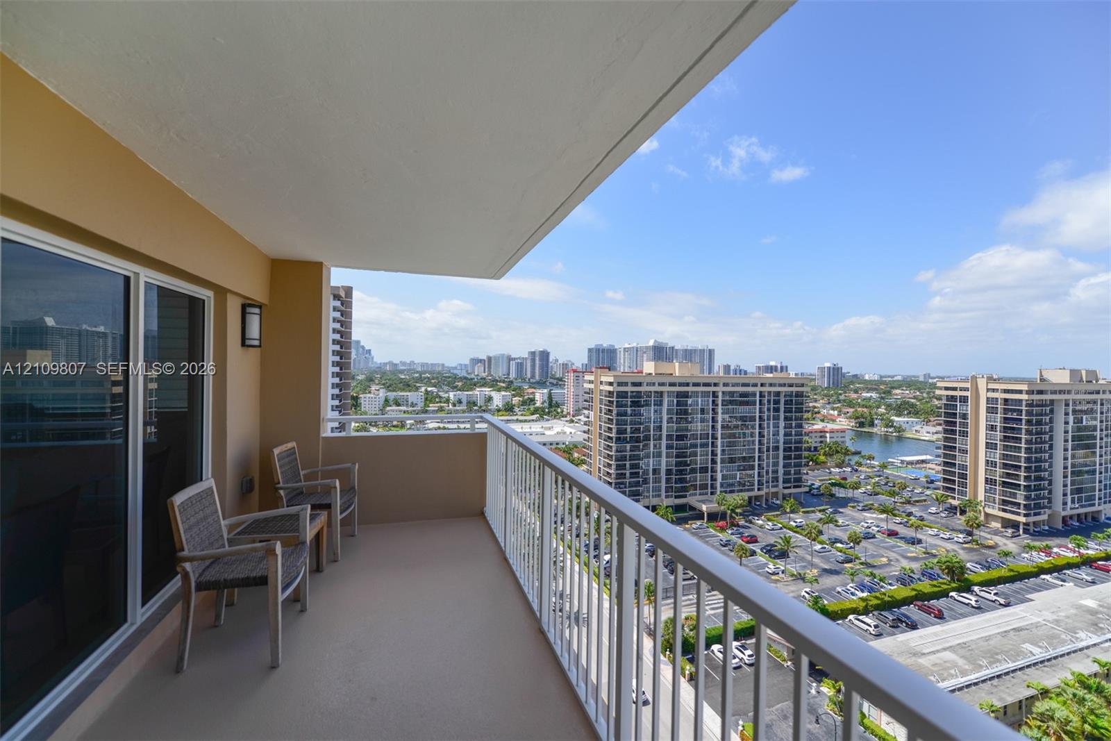 Covered balcony featuring concrete flooring, a white metal railing, and wall-mounted exterior lighting