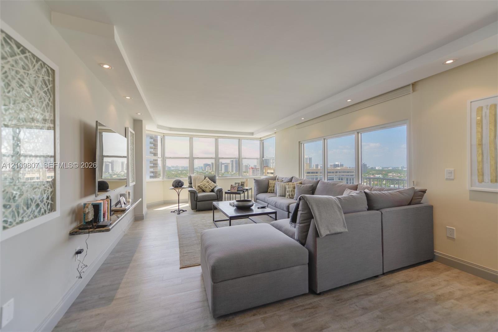 Living area featuring wood-finish flooring, extensive floor-to-ceiling windows, recessed ceiling lighting, and a wall-mounted stone shelf