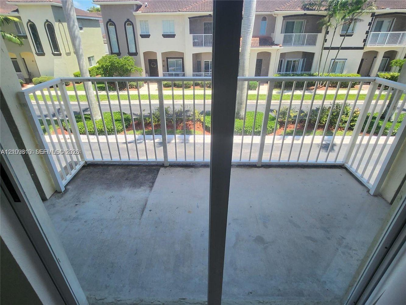 Concrete balcony with a white metal railing and sliding glass door entrance