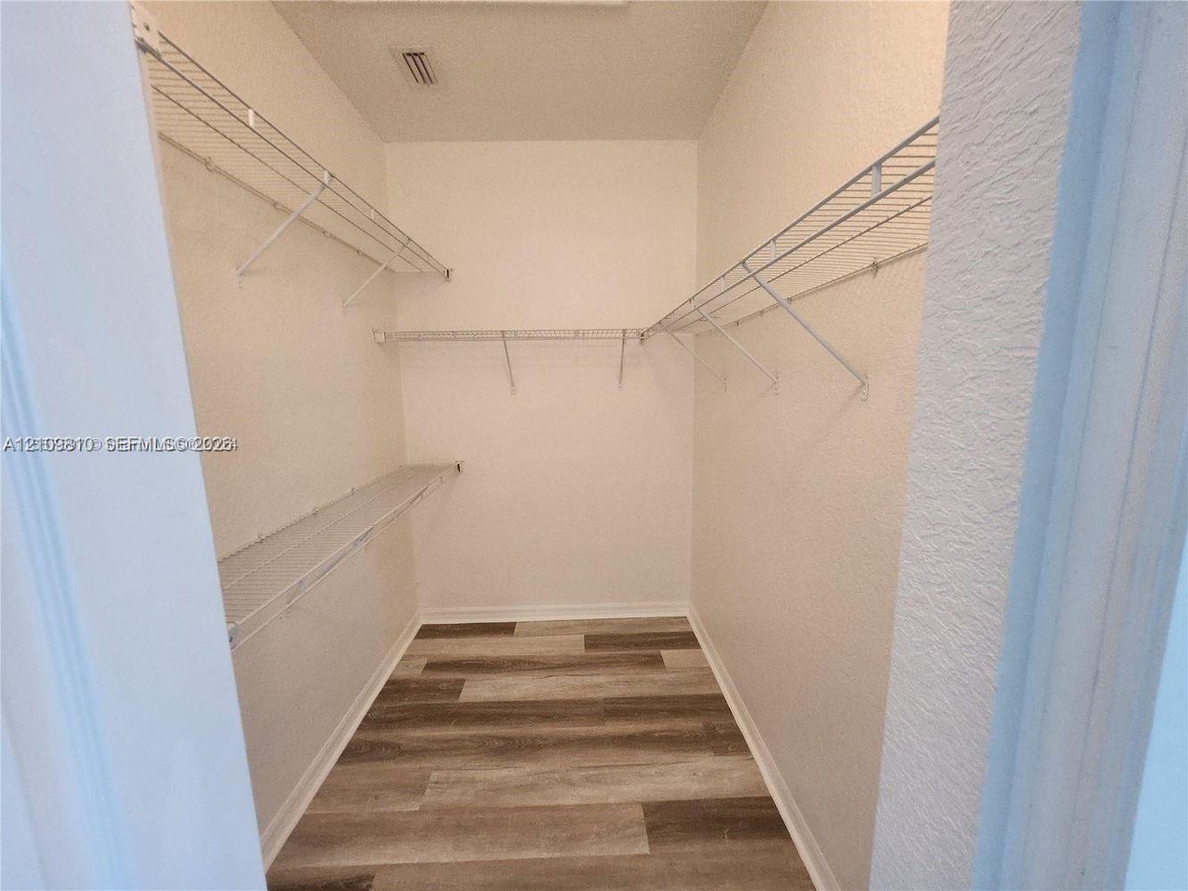 Walk-in storage space featuring wood-finish flooring and tiered wire shelving