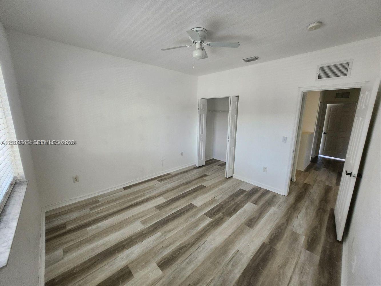 Interior room featuring wood-finish flooring, a ceiling fan, and a closet with bifold doors