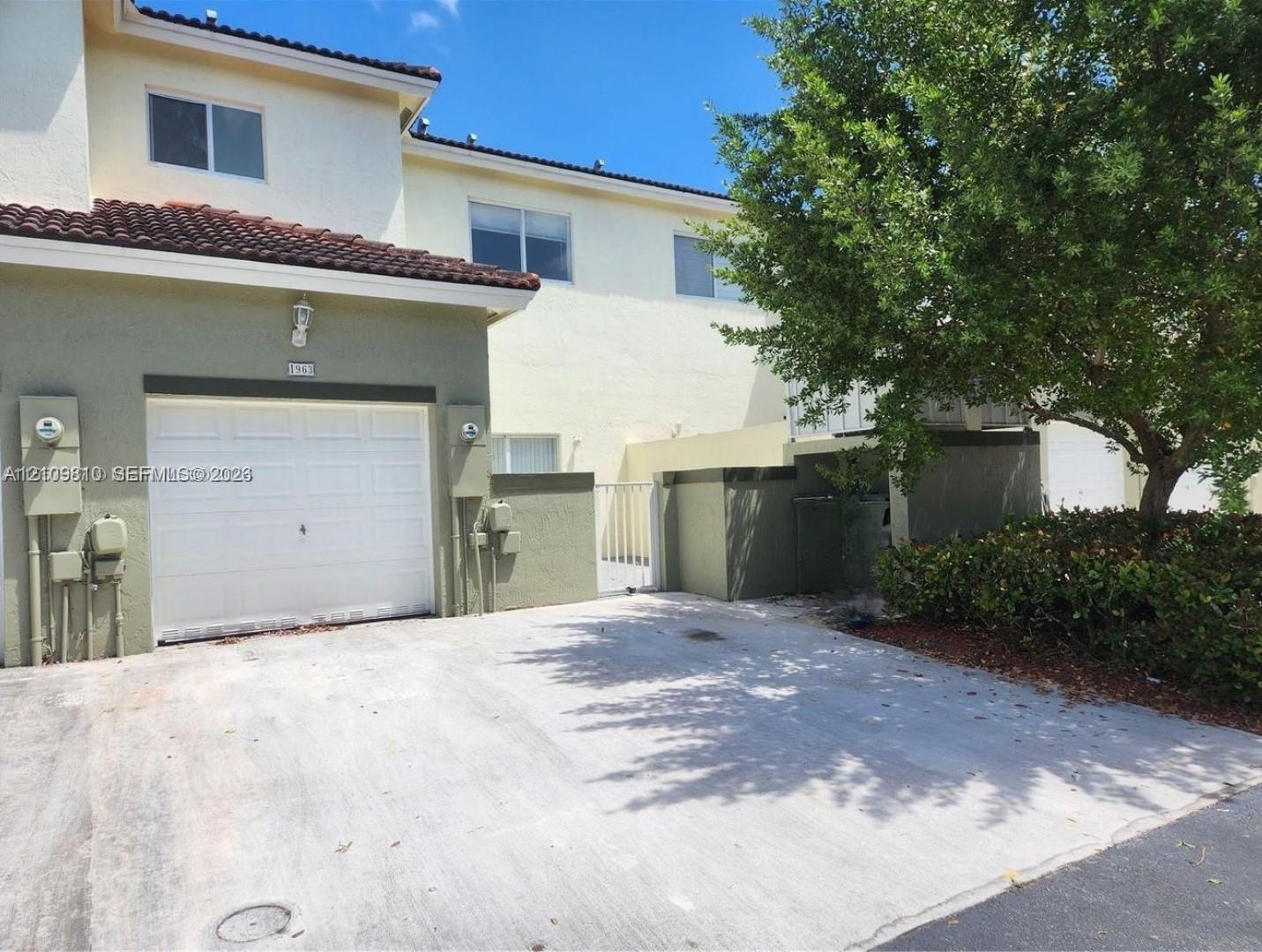 Two-story exterior featuring a stucco facade, tile roof, single-car garage, and concrete driveway