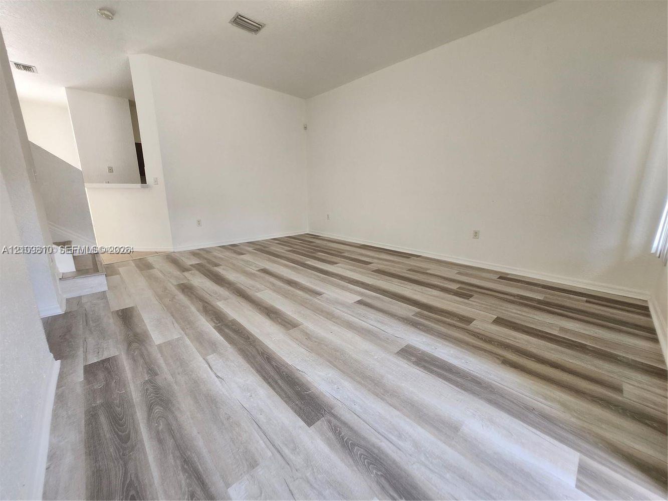 Open-concept interior space featuring multi-tonal wood-finish flooring and neutral wall finishes