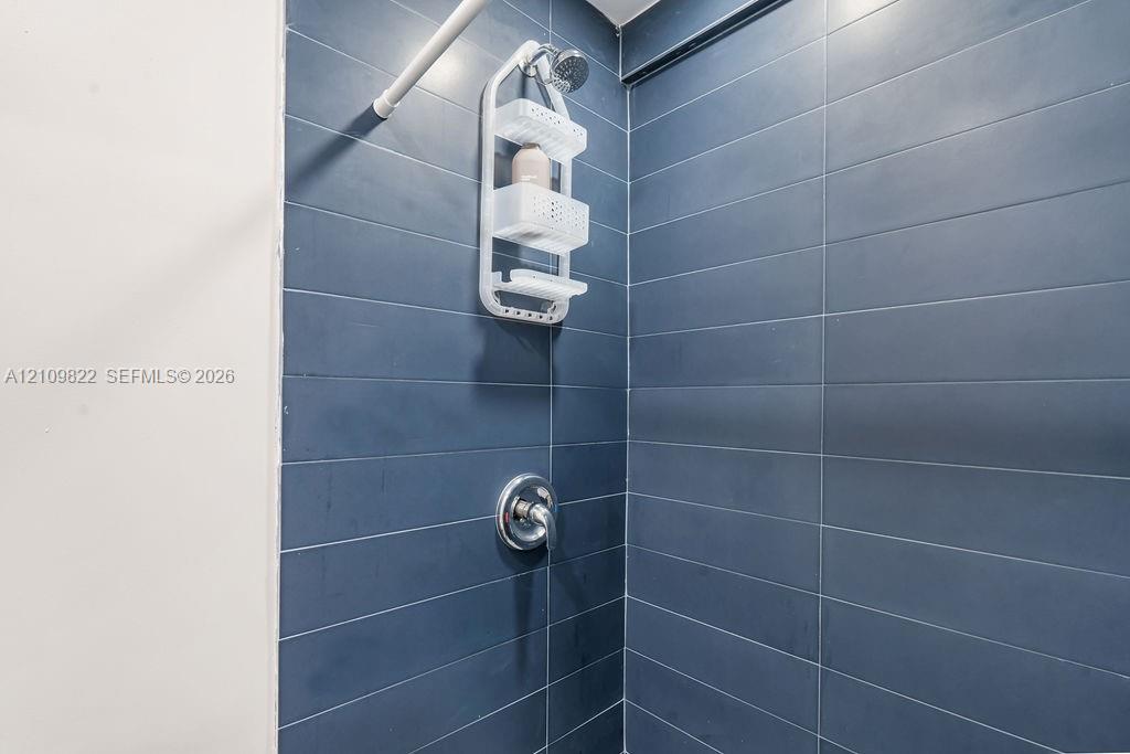 Shower surround featuring large-format dark blue rectangular wall tiles and a polished chrome single-handle mixing valve