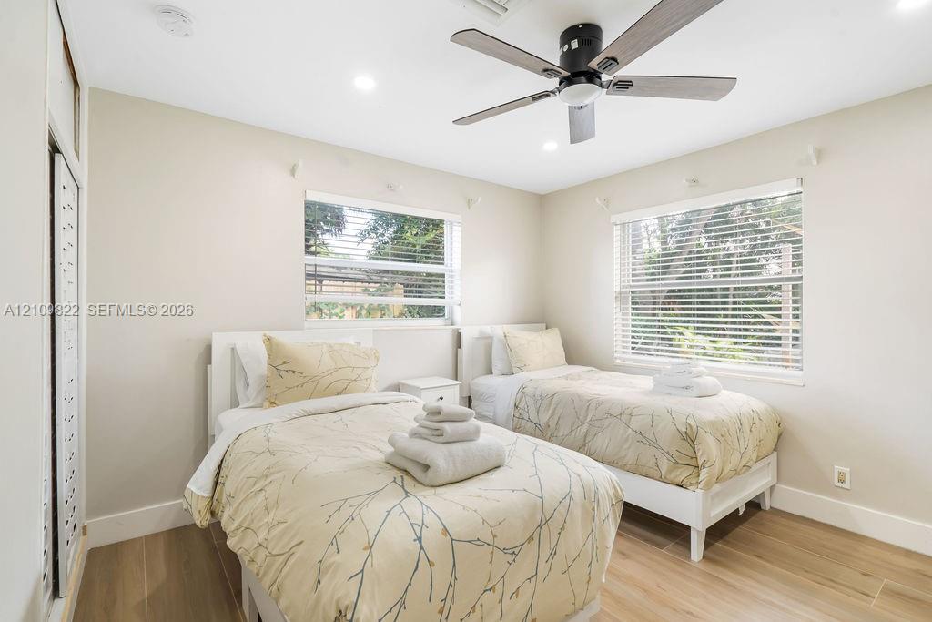 Neutral-toned interior featuring wood-finish tile flooring, recessed ceiling lighting, a matte black multi-blade ceiling fan, and horizontal window blinds