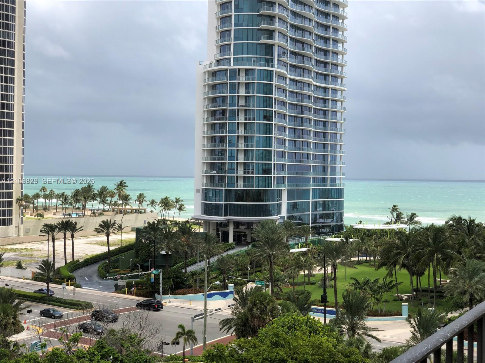 High-rise residential tower featuring a glass-curtain facade, wraparound balconies, and coastal proximity