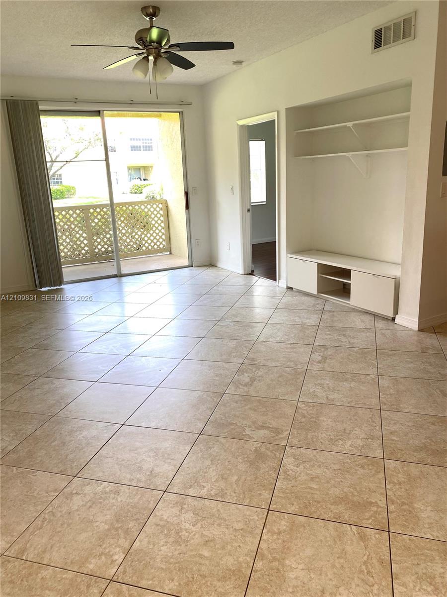 Tiled flooring, built-in cabinetry with integrated shelving, sliding glass door, ceiling fan with light fixture, and covered balcony with lattice railing Tiled flooring, built-in cabinetry with integrated shelving, sliding glass door, ceiling fan with light fixture, and covered balcony with lattice railing