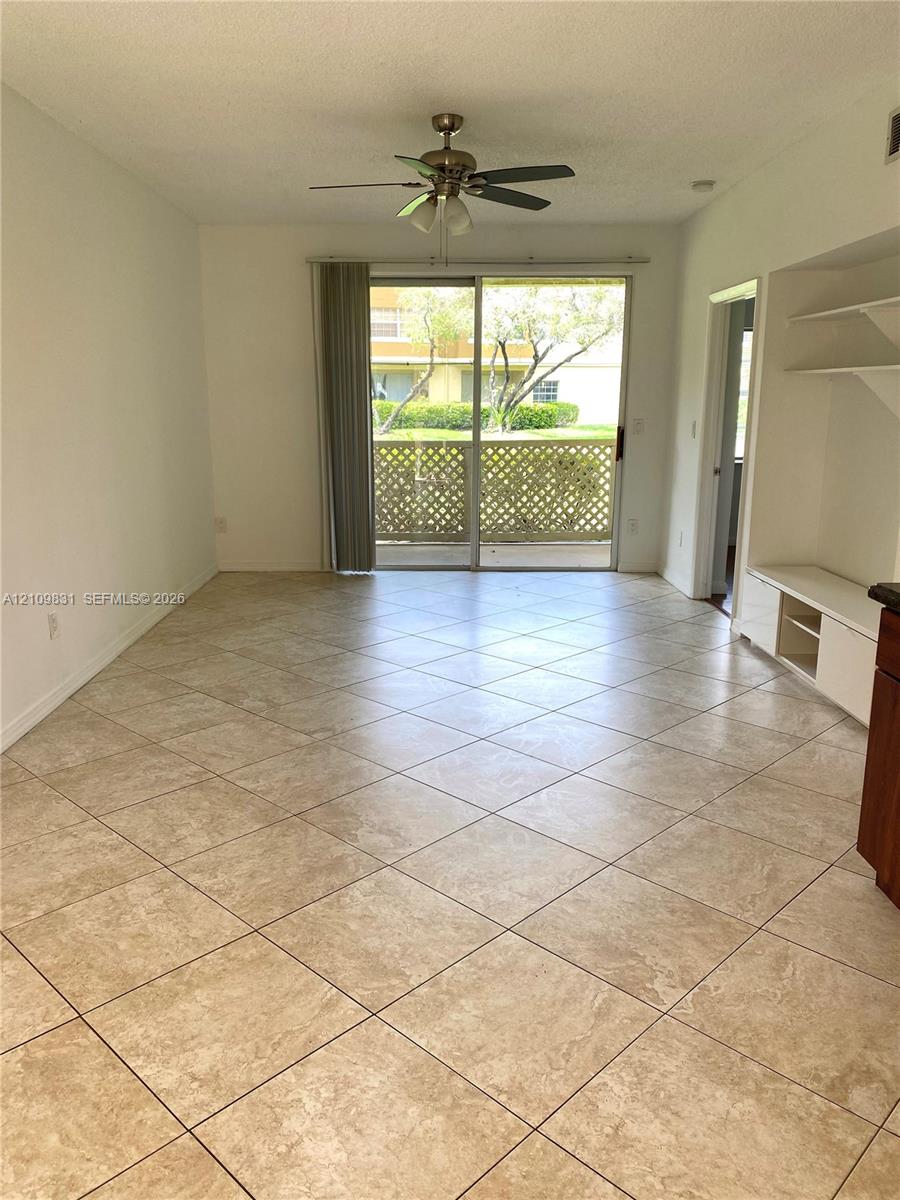 Tiled flooring laid in a diagonal pattern, sliding glass doors, built-in shelving, and a ceiling fan Tiled flooring laid in a diagonal pattern, sliding glass doors, built-in shelving, and a ceiling fan