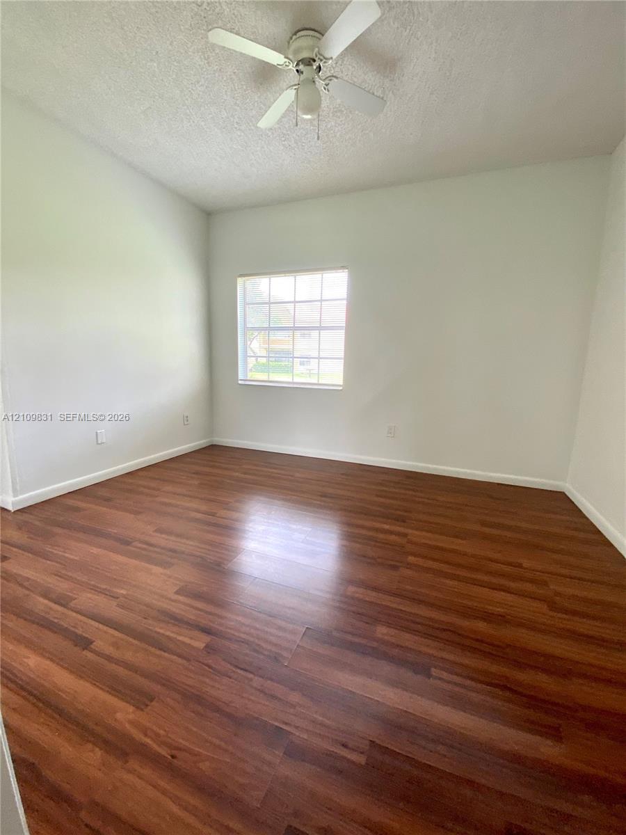 Room featuring wood-finish flooring, a ceiling fan with integrated light, and a multi-pane window