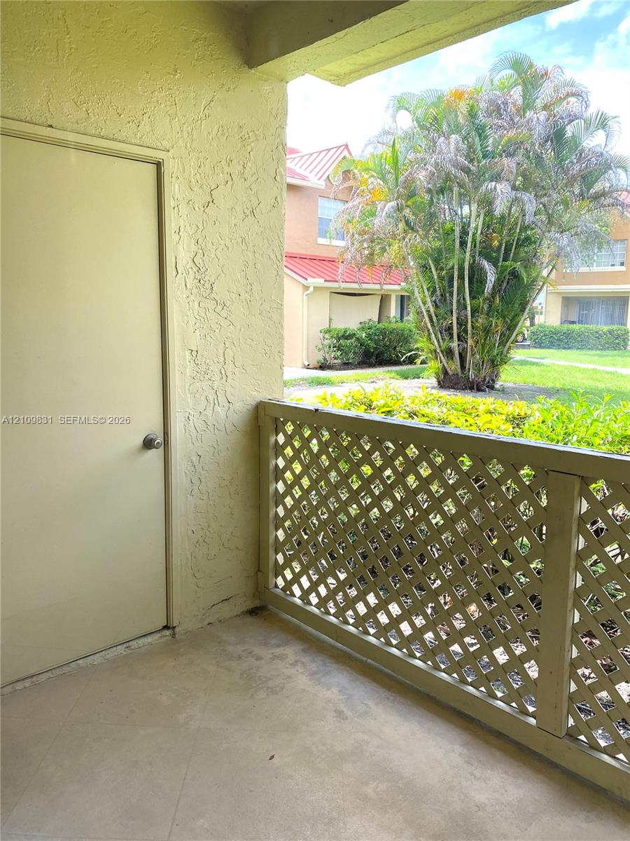 Covered balcony featuring concrete flooring, a dedicated exterior storage closet, and a lattice railing Covered balcony featuring concrete flooring, a dedicated exterior storage closet, and a lattice railing