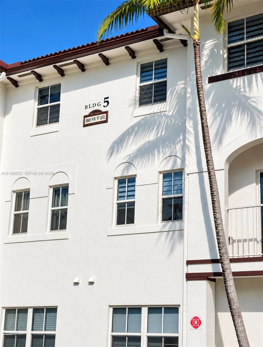Stucco exterior featuring decorative corbels, arched window detailing, and a private balcony with metal railings Stucco exterior featuring decorative corbels, arched window detailing, and a private balcony with metal railings