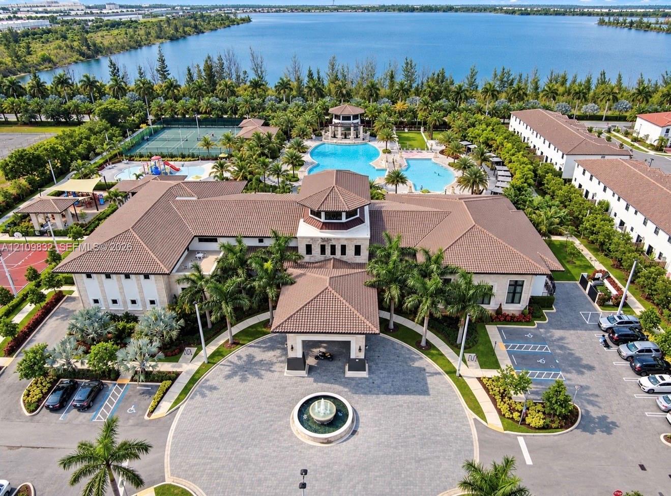 Community clubhouse featuring a porte-cochre, central fountain, swimming pool, tennis court, and water frontage